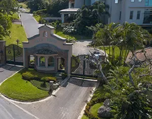 Elegante entrada residencial con puerta de hierro forjado y garita de seguridad, obra de nuestra desarrolladora inmobiliaria.