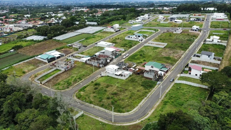 Toma aérea panorámica de un desarrollo urbanístico en crecimiento, con calles y lotes listos.