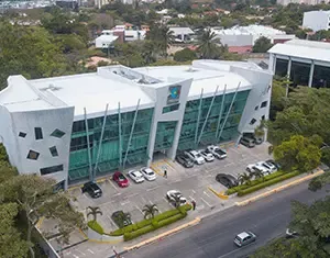 Edificio de oficinas moderno con fachada de vidrio y estacionamiento, un proyecto de nuestra desarrolladora inmobiliaria.